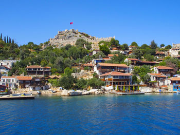 Buildings by sea against clear blue sky