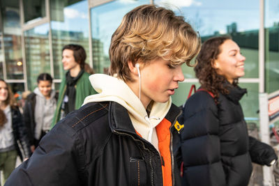 Blond teenager walking with female friend in city