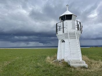 Lighthouse on field against sky