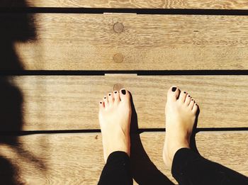 Low section of woman with bare feet on wooden surface