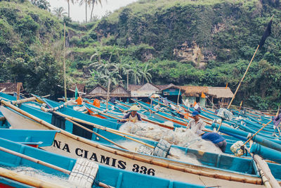 Fishing boats moored on sea against trees