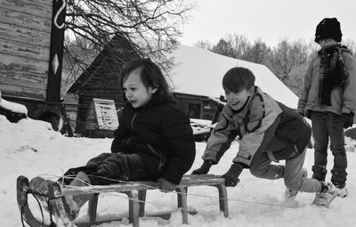Siblings playing with sled on snow