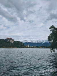 Scenic view of lake bled against cloudy sky.