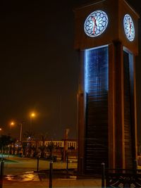 Illuminated street light by building against sky at night