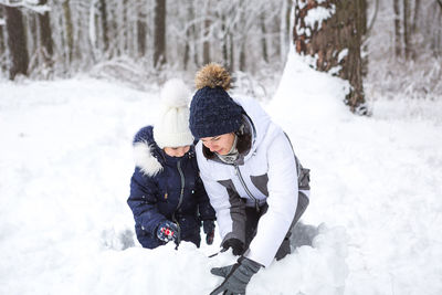 Mom and daughter play snow games, build a fortress, make snowballs. winter entertainment outside,
