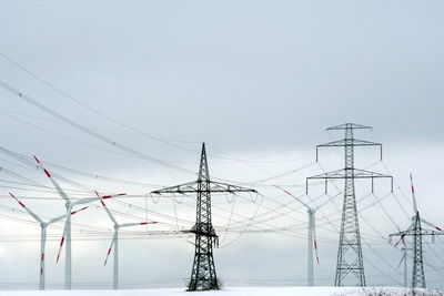 Electricity pylon against cloudy sky during winter