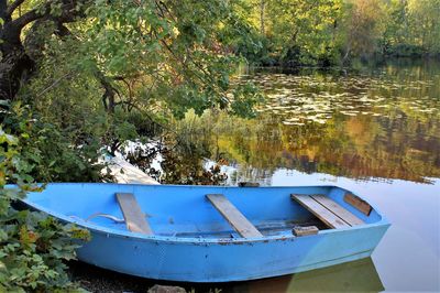 Boat moored in lake by trees