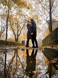 Man and woman standing by lake during autumn. kissing people. 