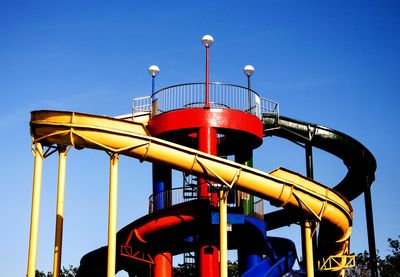 Low angle view of amusement park ride against blue sky