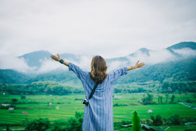 Rear view of woman standing on landscape against sky