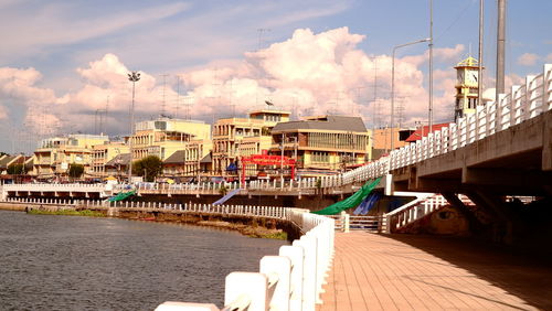 Bridge over river by buildings in city against sky