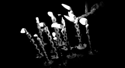 Close-up of illuminated candles against black background