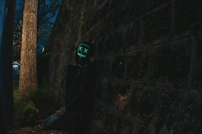 Person standing by tree trunk at night