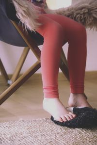 Low section of woman sitting on chair at home