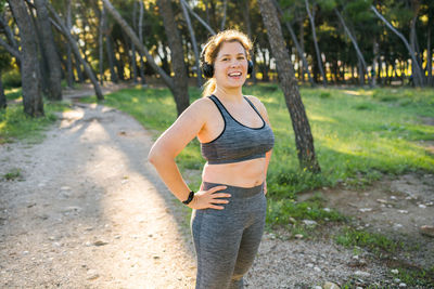 Portrait of young woman standing against trees