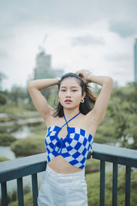 Young woman standing against railing