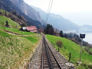 Railroad track by mountain against sky