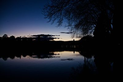 Silhouette trees by lake against sky during sunset