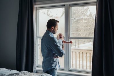 Man looking through window at home