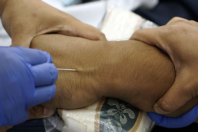 Cropped hand of doctor injecting patient at hospital