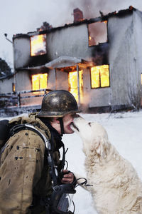 Fireman with rescued dog in front of burning house