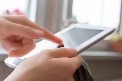 Close-up of woman holding mobile phone at home