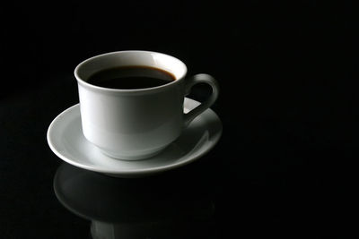 Close-up of coffee cup on table against black background