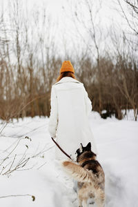 Rear view of woman standing on snow covered field