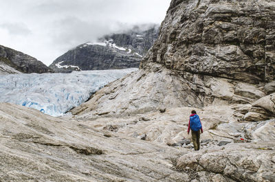 Rear view of female hiker climbing on mountain during winter