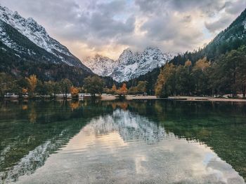 Scenic view of lake by snowcapped mountains against sky