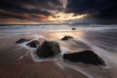 Scenic view of beach against dramatic sky