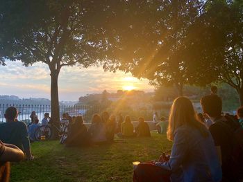 Group of people relaxing in park during sunset