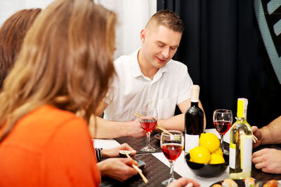 Friends having food and drink on dining table at home