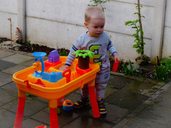 Full length of boy by toys standing at yard