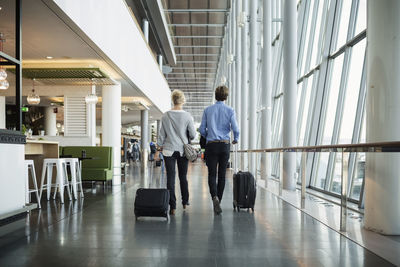 Rear view of businesspeople with luggage walking at airport