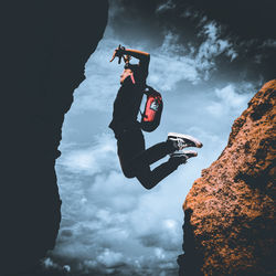 Low angle view of person paragliding on rock against sky