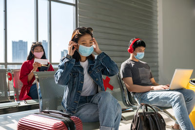 People wearing mask sitting at airport lounge