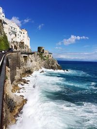 Scenic view of sea by buildings against blue sky