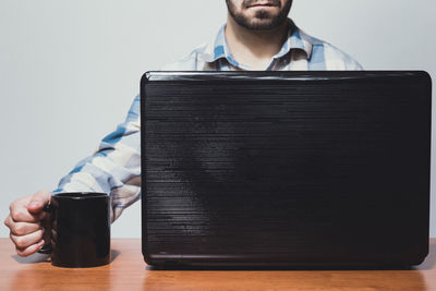 Midsection of man holding mobile phone on table