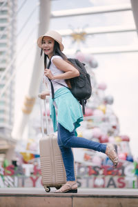 Tourist with luggage standing on steps in city during christmas