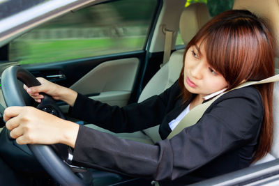 Rear view of woman using mobile phone while sitting in car