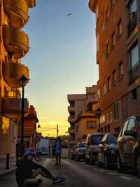 Cars on street amidst buildings in city during sunset
