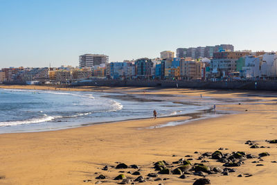 Scenic view of beach and buildings against clear sky