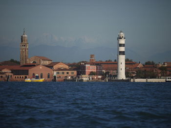 View of buildings by sea against sky in city