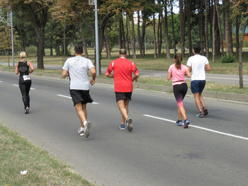 Rear view of people running on plants