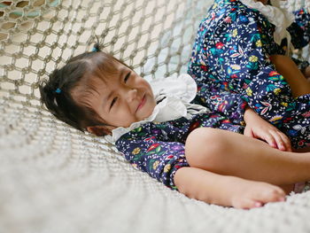 Asian baby girls, 2 years old, enjoys lying down on a hammock together with her older sister at home