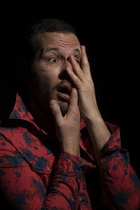 Close-up portrait of man making face against black background