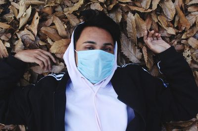 Portrait of young man covered with autumn leaves