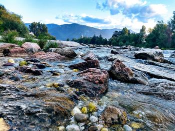 Surface level of rocks in river against sky