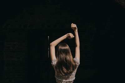 Rear view of woman standing against black background